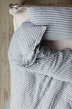 a bed with blue and white striped sheets, pillows and pillow cases on top of it