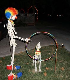 a skeleton playing with a hula hoop in the yard at night time, while another skeleton watches