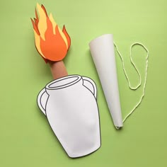 a paper cut out of a white jug with a flame coming out of it on a green surface