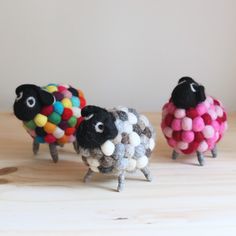 three sheep made out of yarn sitting on top of a wooden table next to each other