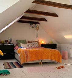 an attic bedroom with a bed and rugs on the floor in front of it