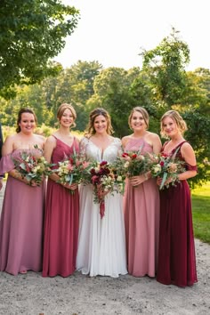 a group of women standing next to each other wearing dresses and holding bouquets in their hands