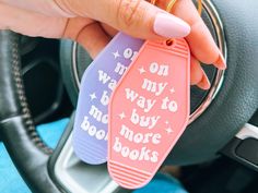 two bookmarks that say on my way to buy more books are being held in a car