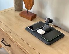 two cell phones sitting on top of a wooden table next to a phone charger