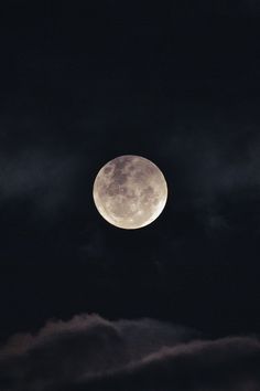 the full moon is seen through dark clouds