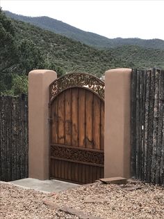 an open wooden gate on the side of a dirt road