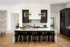 a large kitchen with wooden floors and black cabinetry, along with white countertops