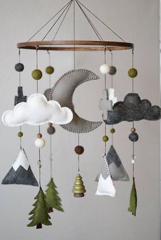 a mobile made out of felt and wood with clouds, trees and mountains hanging from it