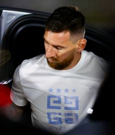 a man with a goatee and beard sitting in a car looking at his cell phone