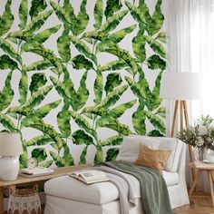 a living room with a white couch and green leaves wallpaper on the wall behind it