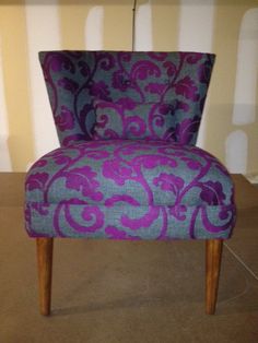 a purple and blue patterned chair sitting on top of a floor next to a wall