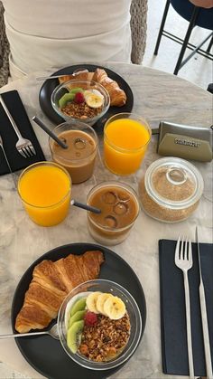 there are many breakfast foods on the table with orange juice and croissants