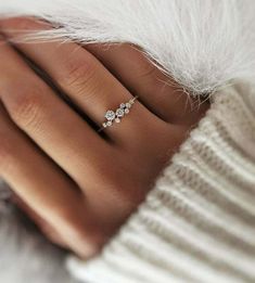 a woman's hand with a diamond ring on top of her finger and white fur