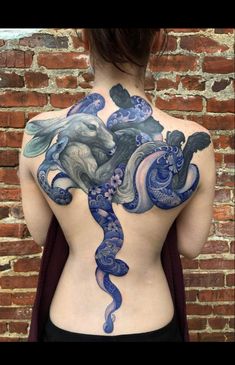 the back of a woman's body is covered in blue and white ink, with an intricate design on it