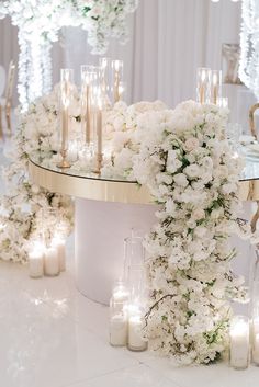 a table topped with lots of white flowers and candles