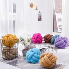 several different colored pillows sitting on top of a bed next to a basket filled with plants