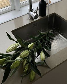 a kitchen sink with flowers in it and water running out of the faucet