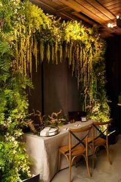 an outdoor dining area with tables and chairs covered in plants, hanging from the ceiling