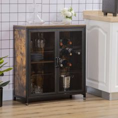 a cabinet with wine bottles and glasses in it next to a potted plant on the floor