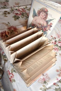 an open book sitting on top of a floral covered table cloth next to other books