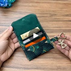 a person holding an open wallet with a keychain and card holder in their hand