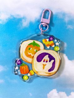 two slices of toast with halloween decorations on them are hanging from a keychain