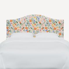 an upholstered headboard with colorful flowers and leaves on the top, against a white background