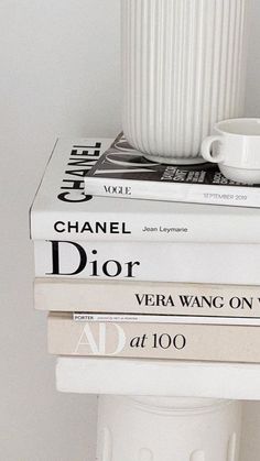 three books stacked on top of each other next to a white cup and saucer