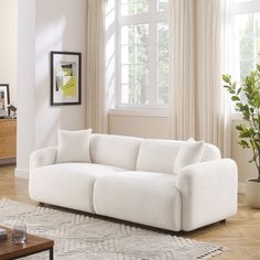 a white couch sitting in front of a window on top of a hard wood floor