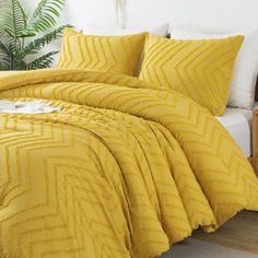 a bed with yellow comforters and pillows