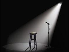 a microphone and stool in front of a spotlight on a black background with a white floor