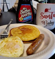 a plate with eggs, sausage and pancakes on it next to a bottle of syrup