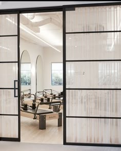 an open glass door leading to a salon with mirrors on the wall and benches in front of it