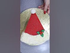 a cake with a santa hat on it is being held by someone's hand