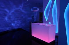 a room with blue and purple lighting on the walls, and a white box in front of it