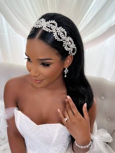 a woman in a wedding dress is wearing a tiara and holding her hand up to her face