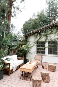 an outdoor patio with wooden furniture and potted plants on the brick floored area