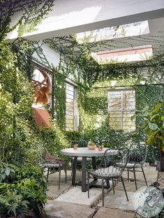 an outdoor dining area with tables and chairs surrounded by greenery on either side of the patio