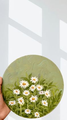 a hand holding a plate with daisies painted on it