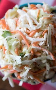 a bowl filled with coleslaw and carrots on top of a checkered table cloth