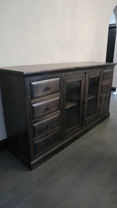 a large wooden dresser sitting on top of a hard wood floor next to a white wall