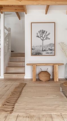 a wooden bench sitting under a tree in a living room next to a stair case