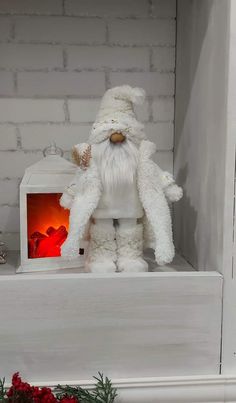 a white stuffed santa claus sitting on top of a shelf