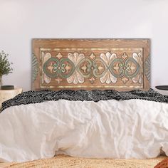 the bed is made up with white linens and wood carvings on it's headboard