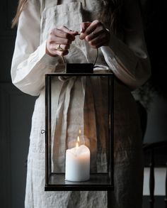 a woman holding a lit candle in a lantern