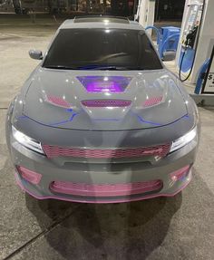 a gray and pink car is parked at a gas station