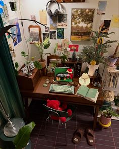 a desk with books, plants and pictures on the wall behind it in a room