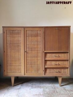 a wooden cabinet with wicker doors and drawers on the bottom, sitting against a wall