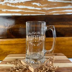 a glass mug sitting on top of a cutting board next to some wood shavings