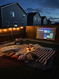 an outdoor movie is set up in the backyard at night with lights strung on it